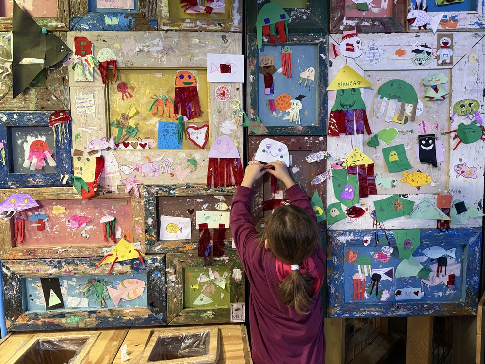 Una bambina realizza un collage colorato durante un laboratorio creativo a Explora